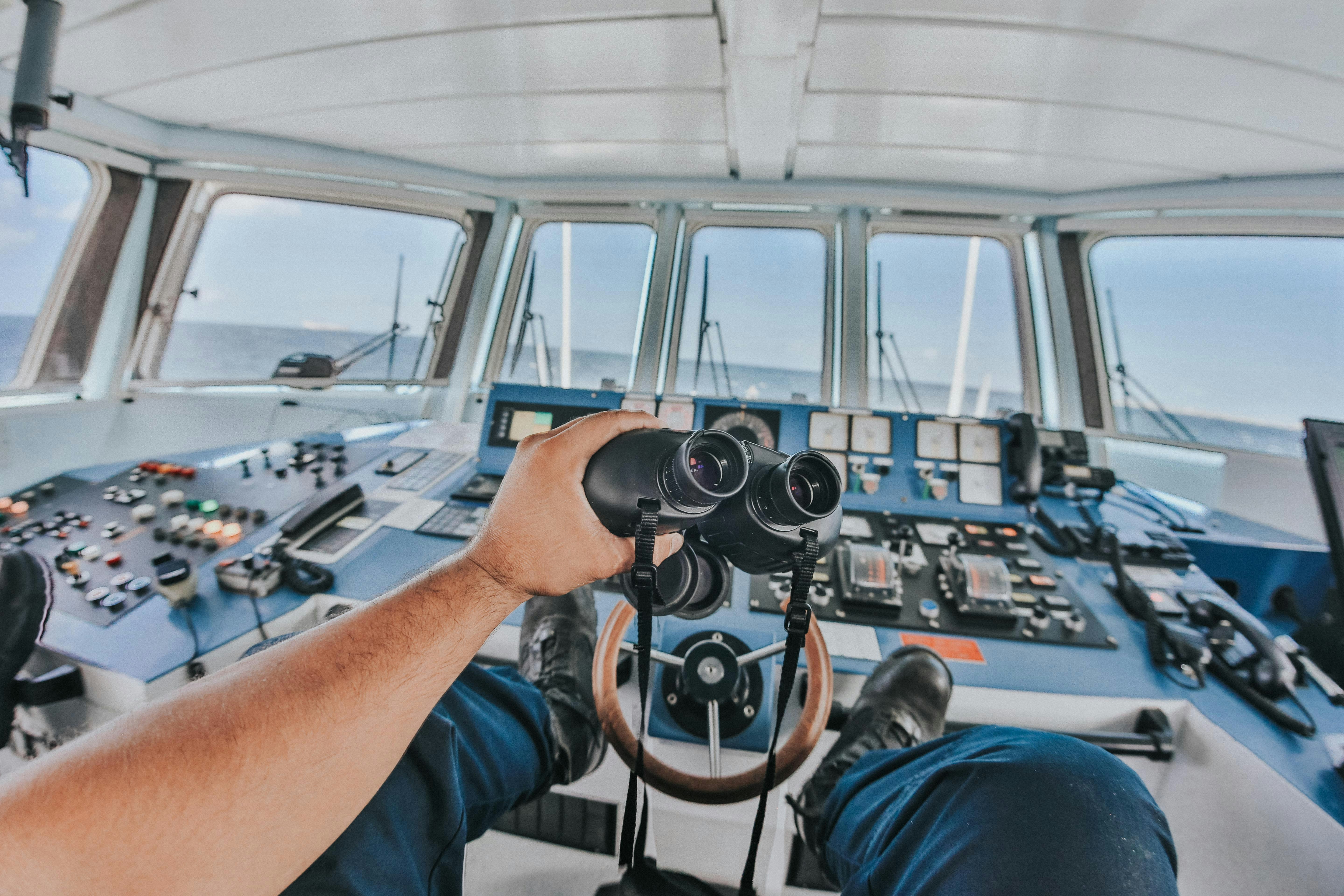 person holding black binoculars inside airplane